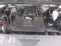 The engine compartment of a 2015 Chevrolet Silverado 1500 featuring a black engine cover with various components and wires visible around it