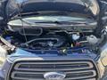 A 2016 Ford Transit 150 with its hood open displaying the engine compartment including various components like hoses and fluid reservoirs
