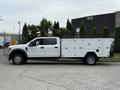 A white 2020 Ford F-550 truck with a utility body featuring storage compartments and a ladder rack on the bed