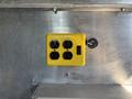 A yellow electrical outlet with four plug ports and a switch mounted on a metallic surface
