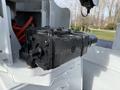 A black hydraulic pump mounted on a vehicle chassis with visible bolts and a connecting shaft