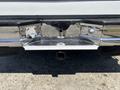 A chrome rear bumper of a 1995 Ford F-250 with a hitch receiver and various features such as reflectors and cutouts for sensors