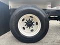 A white rim of a truck tire mounted on a black vehicle chassis with visible bolts and a tire tread design