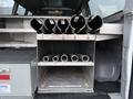 A storage compartment of a 2016 GMC Savana featuring several cylindrical holders and metal tubes organized inside the vehicle