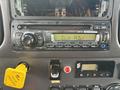 A dashboard of a 2013 Freightliner 114SD showing a car stereo with buttons and a display along with various switches and a yellow cap for fluid reservoir