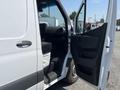 A 2022 Mercedes-Benz Sprinter van with an open passenger door revealing a spacious interior and black seating