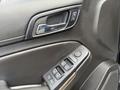 Close-up of the door panel of a 2017 Chevrolet Tahoe featuring the window control buttons and handle in a sleek black finish