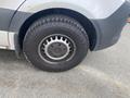 A close-up of the wheel and tire of a 2024 Mercedes-Benz Sprinter featuring a steel rim and all-terrain tire tread pattern
