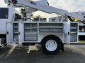 A 2013 International Durastar 4300 utility truck with an Altec lift equipment mounted on it featuring open storage compartments on the side