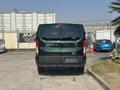 A 2016 Ford Transit 150 viewed from the rear showcasing its dark green color and distinct rear lights