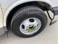 A close-up of a tire on a 2020 Chevrolet Express with a silver rim and green-labeled lug nuts showcasing a rugged tread pattern