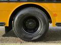 A close-up of a black tire mounted on a yellow vehicle showcasing the tread pattern and wheel design