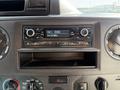 A dashboard view of a 2021 Ford Econoline featuring a car stereo display showing radio frequency and controls for volume and tuning