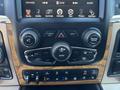 Interior console of a 2015 RAM 1500 featuring digital display and control knobs for audio navigation and climate settings