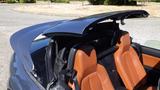 A 2007 Mazda Miata with an open convertible roof and orange leather seats