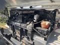 A 2012 Ford E-450 engine compartment showing various components including hoses a battery and a coolant reservoir