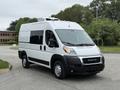 A white 2020 RAM Promaster van with a high roof and large windows parked on a road