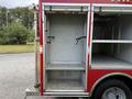 A red fire truck with a large empty compartment showing metal shelves and a smooth floor