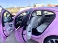 A pink 2020 Jaguar XE with its front and rear doors open revealing a white leather interior and modern dashboard