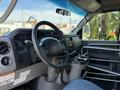 Interior view of a 2013 Ford Econoline with a steering wheel dashboard and controls visible along with a metal frame divider and cup holder