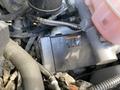 A 2023 GMC Savana engine compartment featuring various mechanical components including wires hoses and a black battery with an attached warning label