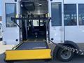A 2020 Chevrolet Express with a lowered access ramp leading into the passenger area equipped with seats and handrails