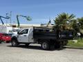 A 2019 Ford F-550 truck with a flatbed body and a white exterior parked on a concrete surface.