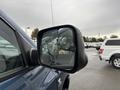 A blue 2006 Dodge Ram 2500 with a cracked side mirror showing raindrops on the glass