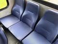 Three blue upholstered seats arranged in a row inside a vehicle