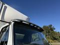 A 2012 Freightliner M2 106 truck with a curved roof visor and distinct front cab design showcasing the cab's large windshield and side mirror