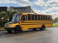 A 2022 Freightliner B2 school bus painted bright yellow with black stripes parked on a street