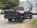 A black 2021 RAM 1500 truck is parked with a distinctive rear design featuring the RAM badge and black rims