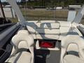 Interior of a 2013 Larson 238 boat featuring white cushioned seats and a red storage compartment in the center