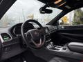 Interior view of a 2019 Jeep Grand Cherokee showcasing the steering wheel dashboard and center console with black leather upholstery and sleek design elements