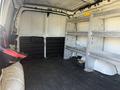 A 2017 Chevrolet Express van interior featuring empty cargo space with metal shelving units on one side and a black back seat on the left