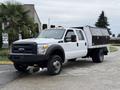 A 2016 Ford F-550 Super Duty truck with a white exterior and a flatbed outfitted with a black storage box on the back