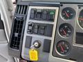 The dashboard controls of a 1999 Freightliner FL80 featuring various buttons for lights wipers and engine fan along with gauges for water temperature and voltage