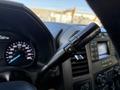 A close-up view of the gear shift lever and dashboard controls in a 2020 Ford F-550 showing the speedometer and audio system