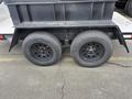 A black trailer with two wheels featuring black rims and tires