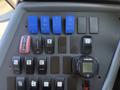 Dashboard controls of a 2013 International CE300 featuring blue and black switches for various functions including dash lights and heating controls