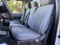 A 2010 Ford F-450 showing the front interior with two gray cloth seats featuring textured designs and seatbelts visible