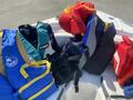 A collection of colorful life jackets in various styles and sizes lying on a boat seat