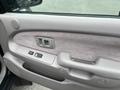 Interior door panel of a 2004 Toyota Tacoma featuring a gray cloth finish power window controls and a door handle