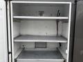 An empty white commercial refrigeration unit with metal shelves and an open door
