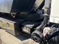 A 2016 Isuzu NPR-HD truck with a black dump bed and visible mechanical components including a battery and air filter