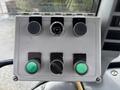 Control panel of a 2009 New Holland T4020 featuring various buttons and switches in a gray and black color scheme with green and black knobs