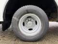 A close-up of a tire and wheel of a 2012 Ford Econoline showcasing a silver rim and a rugged tire tread