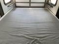 A neatly made bed with a plain gray fitted sheet in a recreational vehicle bedroom