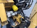 A close-up view of the hydraulic components and cutting mechanism of a 2014 Vermeer Corporation Sweep Stump Cutter featuring yellow and black colors with visible wear and hose attachments
