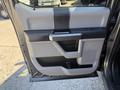 The interior door panel of a 2018 Ford F-150 featuring a gray and black color scheme with a handle and storage compartment